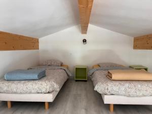 two beds in a room with white walls and wooden floors at Maison l ouline in Montferrer