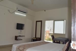 a bedroom with a bed and a tv on the wall at Sri Darshini Comfort 2kms from Hinkal Flyover in Mysore
