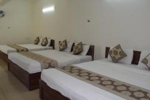 a group of three beds in a room at Sri Darshini Comfort 2kms from Hinkal Flyover in Mysore