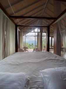 a large bed in a room with a large window at Mihidugiri Eco lodge in Kandy