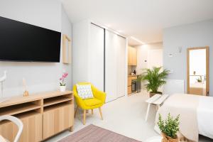 een slaapkamer met een bed en een gele stoel bij Apartamentos La Gringa Centro Gijon I Obra nueva con posibilidad de Parking in Gijón