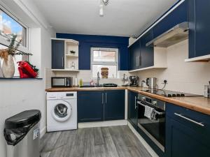 a kitchen with blue cabinets and a washer and dryer at 4br House Popular Ravenhill Road in Belfast +22 photos