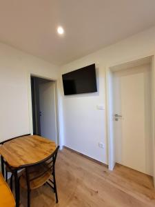 een kamer met een tafel en een televisie aan de muur bij Apartments Crljen in Brodarica +42 foto's