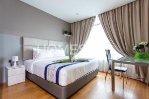a bedroom with a bed and a desk and a window at Vortex Suites Klcc By Homestay in Kuala Lumpur +15 photos
