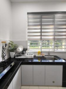 een keuken met een wastafel en een raam met jaloezieën bij Eiman Homestay in Kuala Terengganu
