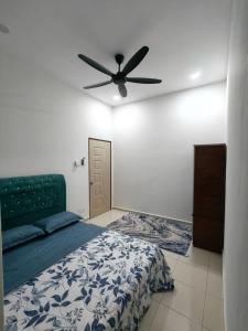 een slaapkamer met een bed en een plafondventilator bij Eiman Homestay in Kuala Terengganu