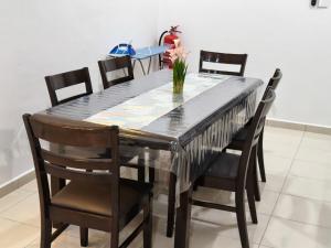 a dining room table with chairs and a vase of flowers on it at Eiman Homestay in Kuala Terengganu