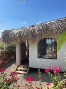 ein kleines Haus mit einem Strohdach und Blumen in der Unterkunft El Cottage de Vaco in Canoas