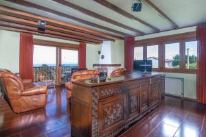 a living room with a desk and chairs and windows at Complejo Rural El Mirador de Ovio in Cuevas