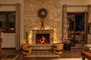 a living room with a stone fireplace with two chairs at the mountain house in parnassus in Eptalofos