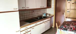 a kitchen with a sink and white cabinets and a table at Casa Checolongo by Sunhome Fiemme in Ziano di Fiemme +3 photos