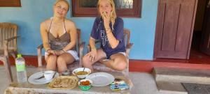 two women sitting in chairs with food on a table at Batti Relax Point Villa & Rooms in Batticaloa +7 photos