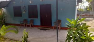 a blue house with chairs and a building at Batti Relax Point Villa & Rooms in Batticaloa