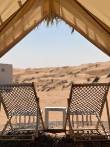 Dos sillas y una mesa en el desierto en Royal desert camp, en Al Raka