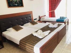 two beds in a hotel room with towels on them at Ceylan Lodge Anuradhapura in Anuradhapura