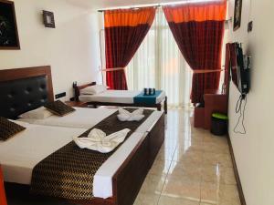 a hotel room with two beds and a flat screen tv at Ceylan Lodge Anuradhapura in Anuradhapura
