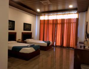 a bedroom with two beds and a window with curtains at Ceylan Lodge Anuradhapura in Anuradhapura