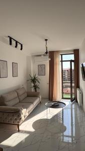 un soggiorno con un divano e un tavolo di vetro di White Bridge Riverside a Kutaisi