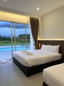 a bedroom with two beds and a view of a pool at วันทน่า พูลวิลล่า เนินมะปราง in Ban Mung