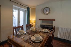 a dining room table with chairs and a clock on the wall at Cottage style with lovely mountain views in Moffat +8 photos