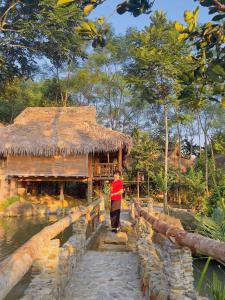 a person standing on a bridge in front of a hut at PuLuong Bản in Lũng Tiềm