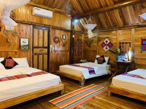 a room with three beds and wooden walls at PuLuong Bản in Lũng Tiềm