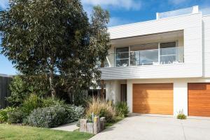 a white house with a wooden garage at Rooftop deck - Central OG - Seaview Luxe in Ocean Grove
