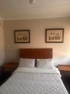 a bedroom with a bed with two tables and two pictures on the wall at Nathi Lodge in New Germany