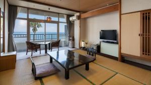 a living room with a table and a view of the ocean at Boyokaku in Amakusa