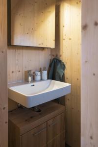 a bathroom with a white sink and a wooden wall at ALTYPIC Mayen d'exception en Valais in Bruson +5 photos