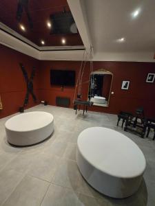 deux tables blanches dans une pièce aux murs rouges dans l'établissement Love room - Jacuzzi - Salle de jeux complète, à Reims