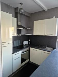 eine Küche mit weißen Schränken und einer Spüle in der Unterkunft Le cocon in Verdun-sur-Meuse