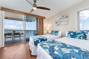 two beds in a bedroom with a view of the ocean at Hololani A204 in Kahana +55 photos