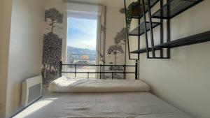 a bedroom with a bed and a window at Au Petit Vélo - Appart Vue sur la Bâtie - Parking Gratuit & Calme - Vienne in Vienne