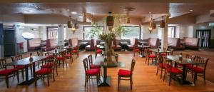 a dining room with tables and red chairs at Lovat Hotel in Perth