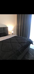 a bedroom with a bed with a black comforter and a window at DAMAC Tower Amman boulevard برج داماك - عمان البوليفارد العبدلي in Amman +30 photos