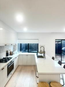 ポートアーリントンにあるCoastal on Clarkeの白いキャビネットと大きな窓のあるキッチン