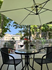 Una mesa con dos copas de vino y una sombrilla. en Depandance Blue Hotel, en Cesenatico