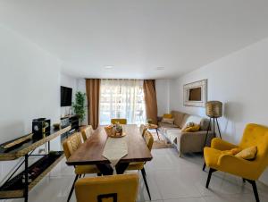 a living room with a wooden table and yellow chairs at Luxury Bahia Sea Views by Deihu Experiences in Los Cristianos