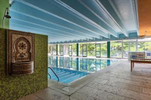 a pool in a building with blue ceilings and windows at Park Hotel Jolanda in San Zeno di Montagna