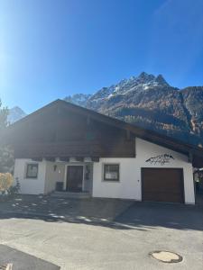 a building with a garage with mountains in the background at Apart Helga in Oberlängenfeld