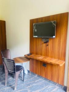 ein Zimmer mit einem Fernseher und einem Tisch und einem Stuhl in der Unterkunft River Side Gorilla Resort Mussoorie in Masuri
