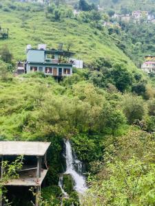 ein Haus auf einem Hügel mit einem Wasserfall in der Unterkunft River Side Gorilla Resort Mussoorie in Masuri