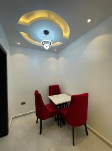 a dining room with a table and two red chairs at HOMEWORTH SPACES - Shortlet Apartmemt in Alimosho