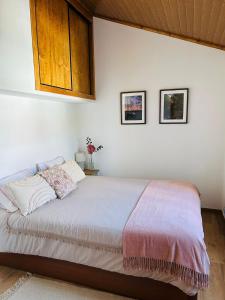 a bedroom with a bed and two pictures on the wall at Casinha da Relva 