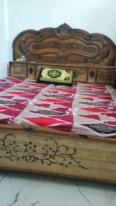 a wooden bed with a red and white quilt on it at Nangli Homestay in Meerut