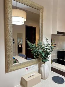 Un espejo en una pared con un jarrón con una planta. en TDJ Japandi Studio in Tambuli Seaside Living Fully Equipped, en Maribago