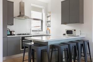 een keuken met grijze kasten en een aanrecht met krukken bij Luxury Fully Equipped Kitchen Ormeau Park in Belfast