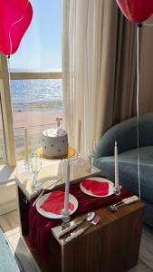a table with a cake and red plates and balloons at SEAVIEW HOTEL in Umm Lujj