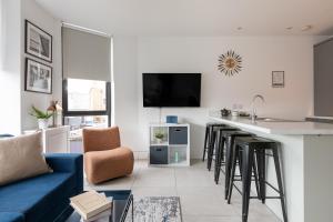 een woonkamer met een blauwe bank en een bar met krukken bij Luxury Fully Equipped Kitchen Ormeau Park in Belfast